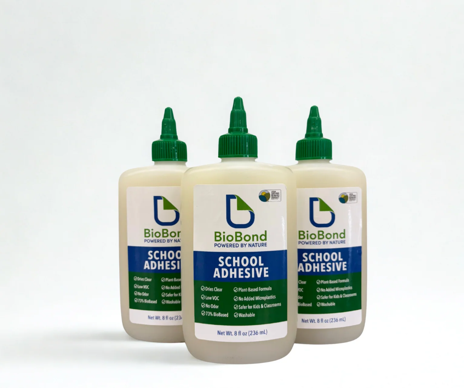 Three school-adhesive bottles with green caps and coordinated blue, green, and white labels that emphasize classroom use and concise product benefits.